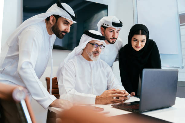 Group of middle-eastern corporate business people wearing traditional emirati clothes meeting in the office in Dubai - Business team working and brainstorming in the UAE